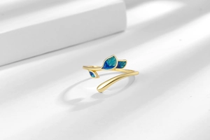 Detail of adjustable gold ring featuring vibrant blue gradient enamel leaf motifs