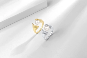 Detail of adjustable pearl rings in gold and silver finishes with shell-inspired design