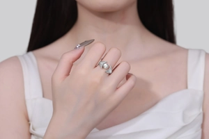 Detail of silver shell ring with a white pearl on finger showing elegant ocean style