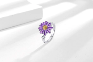 Close-up of adjustable purple daisy spinner ring with yellow core and cubic zirconia