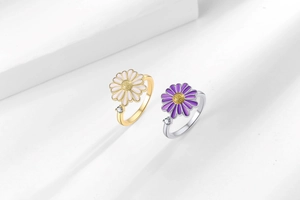 Detailed macro view of rotating daisy rings with white and purple enamel flower petals