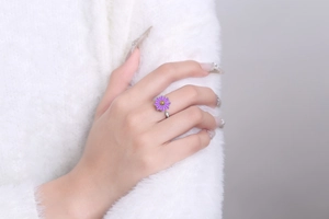 Detailed close-up of rotating purple daisy ring on finger with silver adjustable band