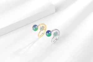 Close-up of gold and silver adjustable rings with Hamsa hand and yin yang enamel motifs