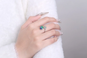 Detail of enamel Yin Yang and Hamsa Hand rotating ring worn with a plush sweater