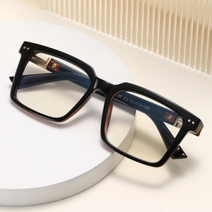 Fashionable square black frame glasses with gold metal accents on a white display tray