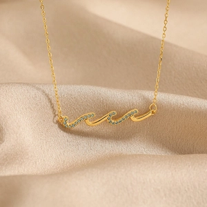 Collier élégant vague dorée avec zircons bleus sur fond de satin champagne soyeux