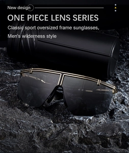 Close-up of sporty one-piece lens sunglasses with gold metal top bar on dark rock surface