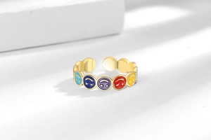 Close-up of golden adjustable ring with colorful enamel smiley faces on white platform