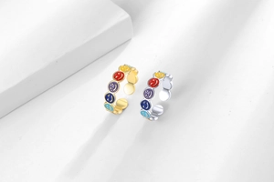 Macro detail of gold and silver rings featuring colorful enamel smiley face patterns