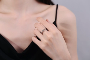 Detail of silver geometric knot ring on model's finger with mirror polished finish