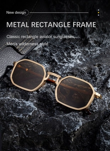 Close-up of golden square metal sunglasses with brown lenses on a rugged dark rock