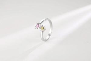 Détail d'une bague ouverte en argent avec zircons en forme de cœur rose et jaune