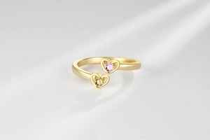 Détail de la bague cœur bypass avec zircons rose et jaune sur monture dorée