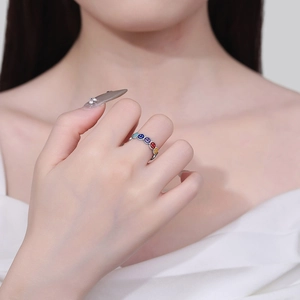 Silver open ring featuring colorful enamel smiley face patterns on model finger