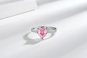 Macro shot of silver ring with pink heart-shaped crystal and side diamond accents