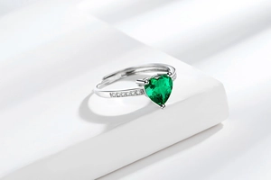 Macro shot of heart-shaped emerald green zircon ring with sparkling side diamonds