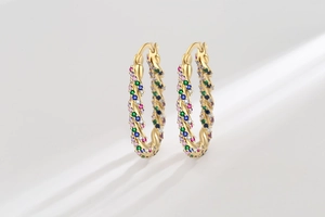 Macro detail of gold-plated twisted hoop earrings set with colorful zircon crystals