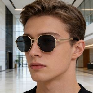 Close-up of golden octagonal sunglasses with metal temples worn by a male model