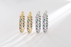 Detail of gold and silver twisted hoop earrings with multicolored zircon stones