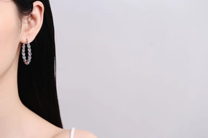 Detail of twisted hoop earring with multi-colored crystals on a model's ear
