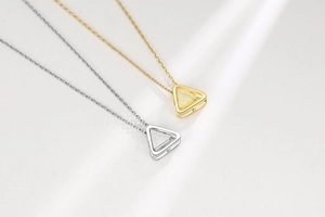 Detail view of gold and silver minimalist hollow triangle pendants on fine link chains