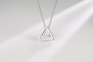Macro detail of silver triangle pendant with polished outer frame and brushed inner texture