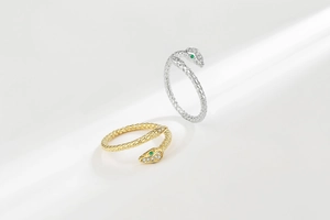Macro detail of snake rings with green gem eyes and sparkling white crystal paving