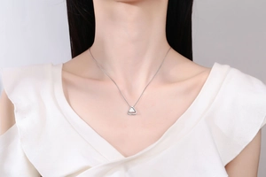 Close-up of a minimalist silver triangle pendant necklace with white inlay on a model