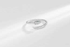 Macro detail of silver snake ring featuring sparkling pavé diamonds and emerald green eyes