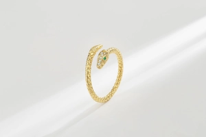 Detailed view of gold snake ring with white crystals and emerald green gemstone eyes