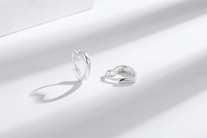Macro shot of silver heart-shaped hoop earrings with polished finish on white background