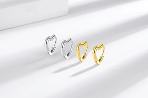 Macro shot of minimalist hollow heart hoop earrings in polished gold and silver finishes