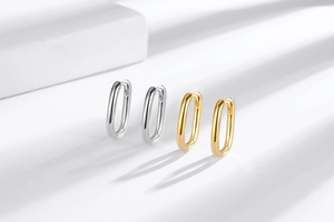 Close-up of heart-shaped hollow earrings in gold and silver with elegant shadow play