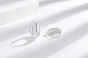 Detailed close-up of polished silver hoop earrings with elegant light and shadow effects