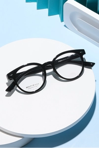 Detail view of black round eyeglass frame with printed model number on white stand