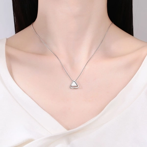Minimalist silver triangle pendant necklace with layered geometric design on model's neck