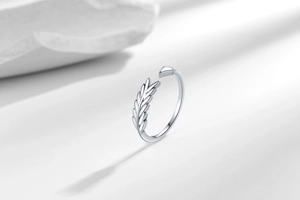 Detailed view of silver leaf pattern open ring on minimalist white stone display