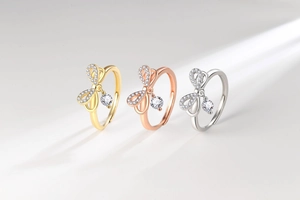 Detailed view of shimmering bow rings with dangling crystals in gold, silver, and rose gold