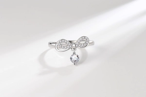 Detail of silver bow ring with sparkling zircons and a round hanging crystal drop