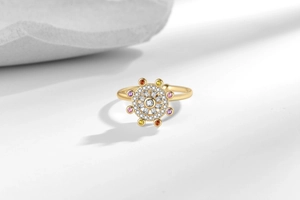 Detailed macro of golden rotating star sign ring with colorful zircon stones on white surface