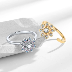 Rotating daisy rings in gold and silver with zircon flower petals on stone base