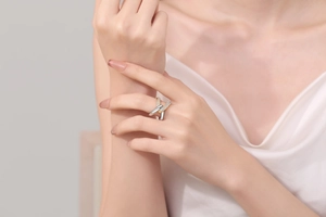 Detail shot of criss-cross X-shaped ring with sparkling crystals on female finger