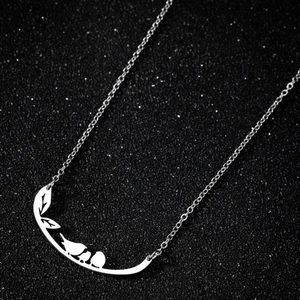 Détail du pendentif oiseaux sur branche en argent avec finition polie sur fond noir