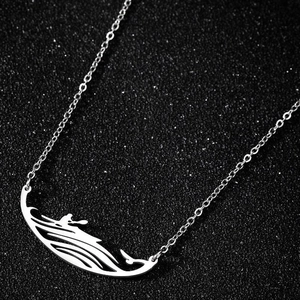 Vue macro du collier kayak argenté avec silhouette de vague sur fond noir texturé