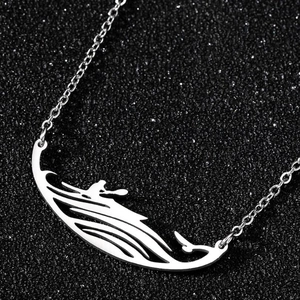 Gros plan d'un collier pendentif canoë en argent sur un support à bijoux noir texturé