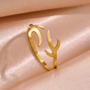 Macro view of adjustable golden antler ring on soft pink silk fabric background