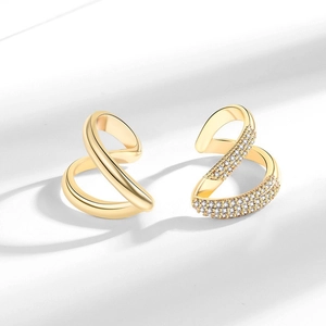 Modern gold X-shaped twisted ear cuffs set with micro-pave crystals on white background