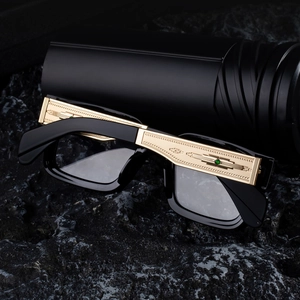 Détail de lunettes de soleil noires avec branches dorées larges et pierres précieuses vertes