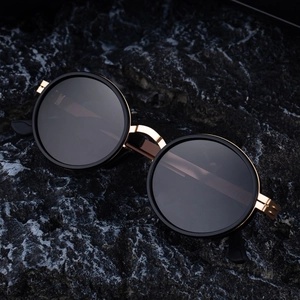 Retro oval polarized sunglasses with gold metal frame on a dark textured rock background