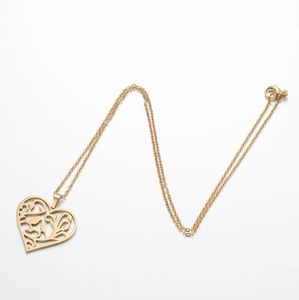 Détail du pendentif cœur évidé doré avec motif filigrane complexe et chaîne fine en O